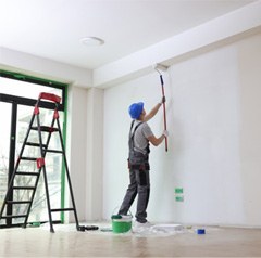 Man painting the walls in empty room